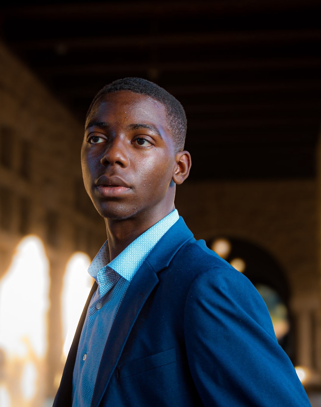 Okezue's headshot wearing a blue formal suit looking to his right